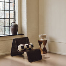 Load image into Gallery viewer, Lifestyle shot of cream and brown wool bouclé checkered bolster cushion on wavy rattan chair