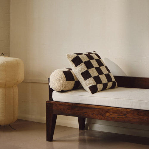 Lifestyle shot of cream and brown wool bouclé checkered square cushion on daybed