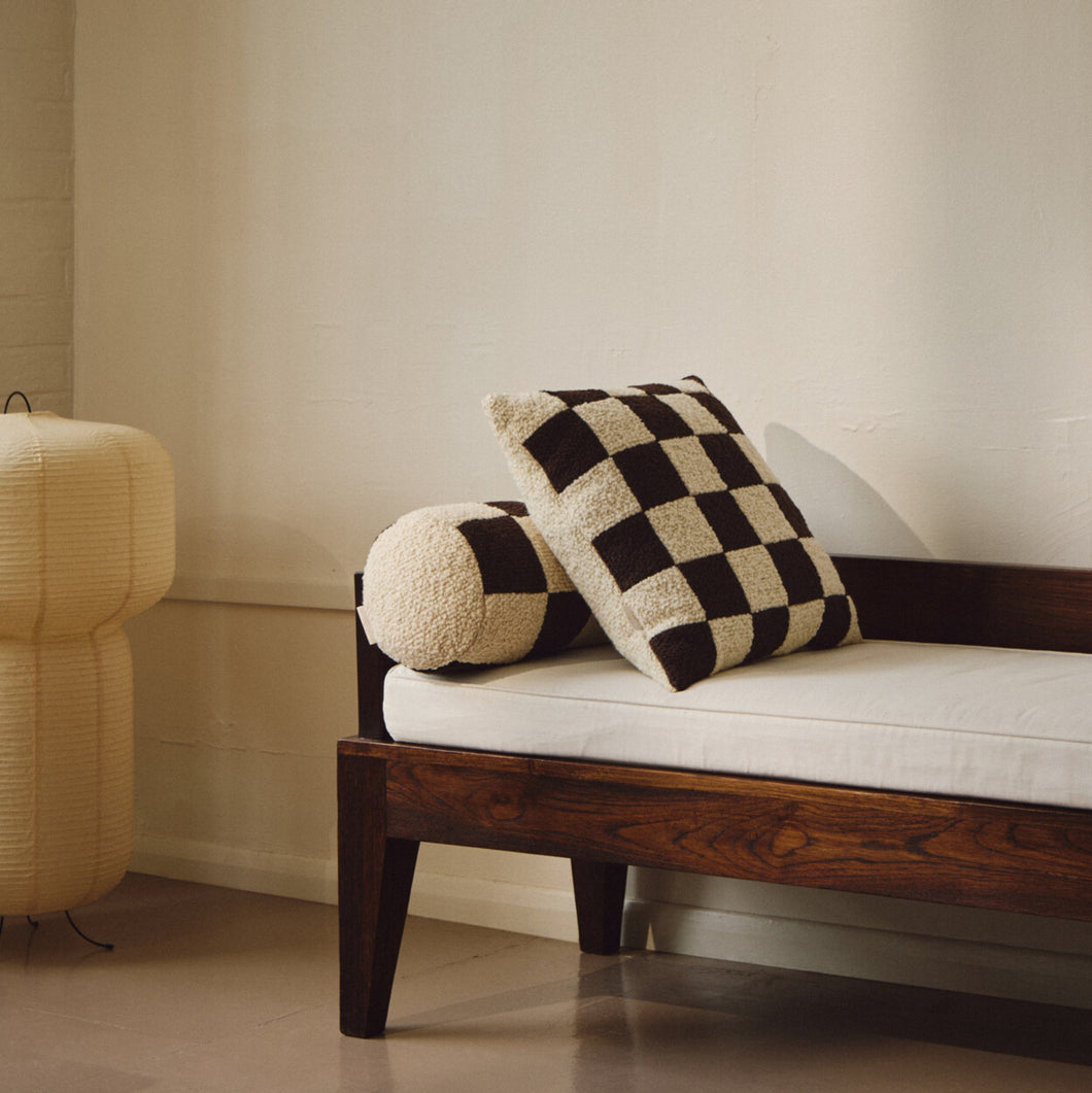 Lifestyle shot of cream and brown wool bouclé checkered square cushion on daybed