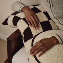 Load image into Gallery viewer, Lifestyle shot of hands resting on cream and brown wool bouclé checkered square cushion
