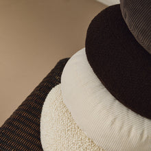 Load image into Gallery viewer, Lifestyle close up of stack of round wool and corduroy cushions on rattan chair
